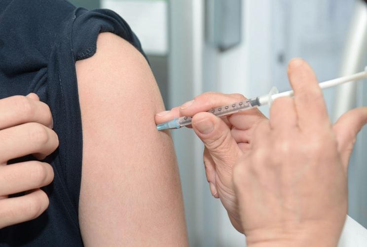 Doctor injecting a vaccine to another person